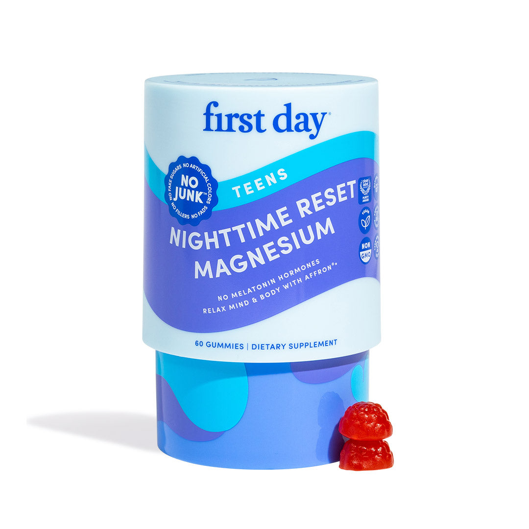 A container labeled Teens’ Nighttime Reset Magnesium sits upright, with two berry-shaped red gummies beside it. The label states No Junk and the calming supplement for teens includes 60 magnesium gummies.