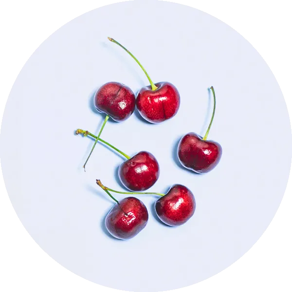 Six red cherries with green stems arranged in a loose cluster on a light, pale blue background.